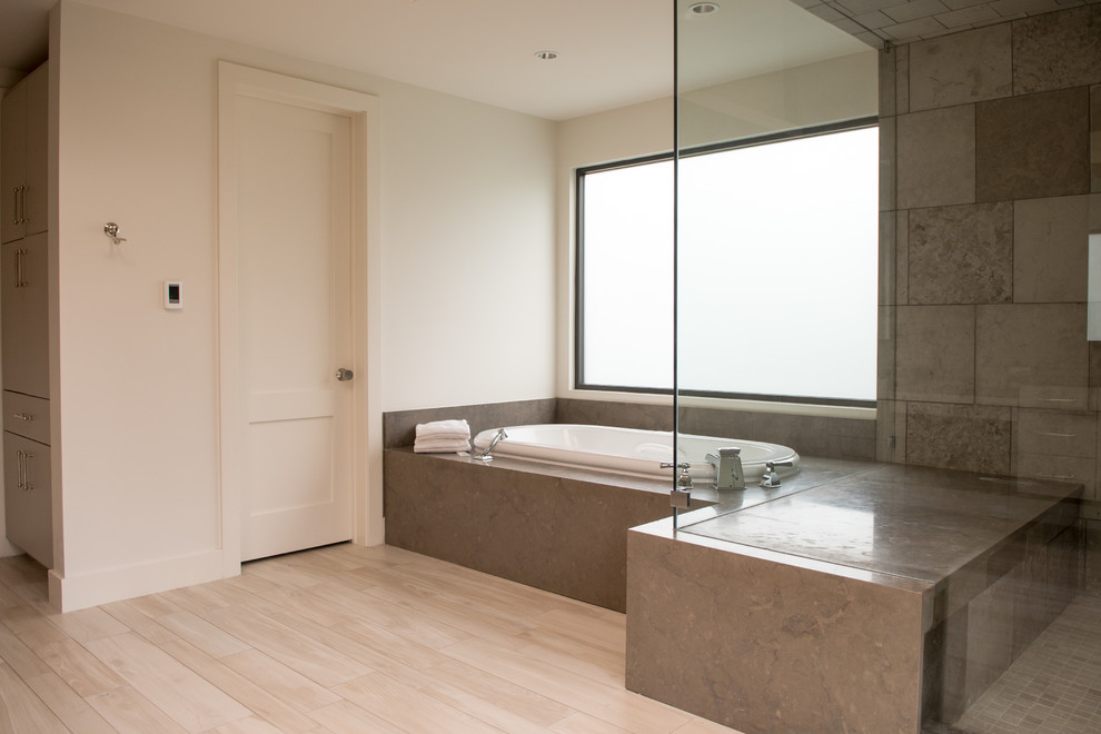 Mid-sized transitional master gray tile and cement tile light wood floor and beige floor drop-in bathtub photo in Dallas with flat-panel cabinets, gray cabinets, gray walls, a drop-in sink, concrete countertops and a hinged shower door