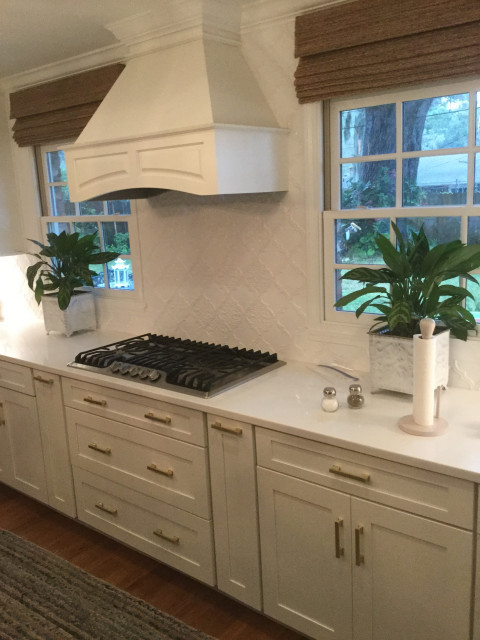Example of a large transitional l-shaped medium tone wood floor and brown floor eat-in kitchen design in Atlanta with a farmhouse sink, shaker cabinets, white cabinets, marble countertops, white backsplash, an island, white countertops and stainless steel appliances