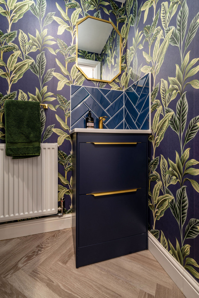 This is an example of a medium sized modern cloakroom in West Midlands with freestanding cabinets, blue cabinets, blue tiles, porcelain tiles, blue walls, vinyl flooring, a built-in sink, quartz worktops, grey floors, white worktops, a feature wall, a freestanding vanity unit and panelled walls.