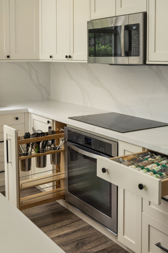 Mid-sized transitional l-shaped laminate floor and brown floor eat-in kitchen photo in Miami with a drop-in sink, shaker cabinets, medium tone wood cabinets, quartz countertops, white backsplash, quartz backsplash, stainless steel appliances, an island and white countertops