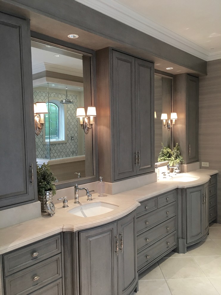 Large beach style master bathroom with raised-panel cabinets, grey cabinets, a freestanding tub, a double shower, a one-piece toilet, beige tile, stone slab, beige walls, travertine floors, an undermount sink, marble benchtops and beige floor.
