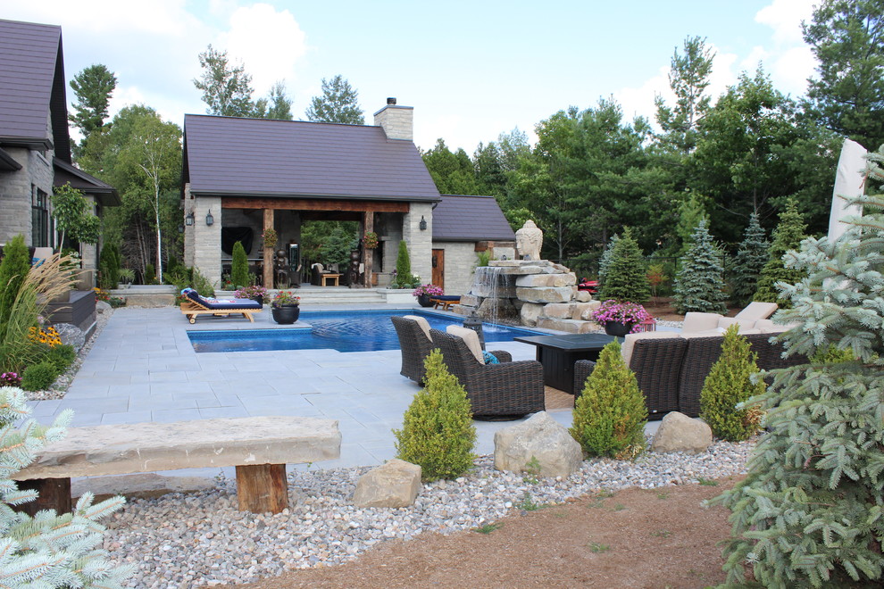 Large modern backyard l-shaped natural pool in Ottawa with concrete pavers and a water feature.