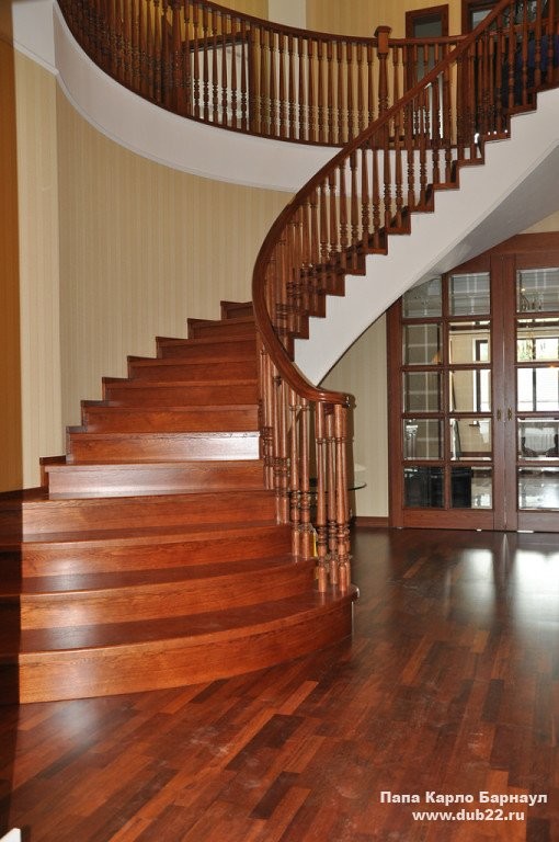 This is an example of an expansive traditional wood curved staircase in Other with wood risers and wood railing.