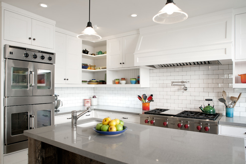 This is an example of a mid-sized transitional u-shaped kitchen in Los Angeles with quartz benchtops, stainless steel appliances, with island, white splashback and subway tile splashback.