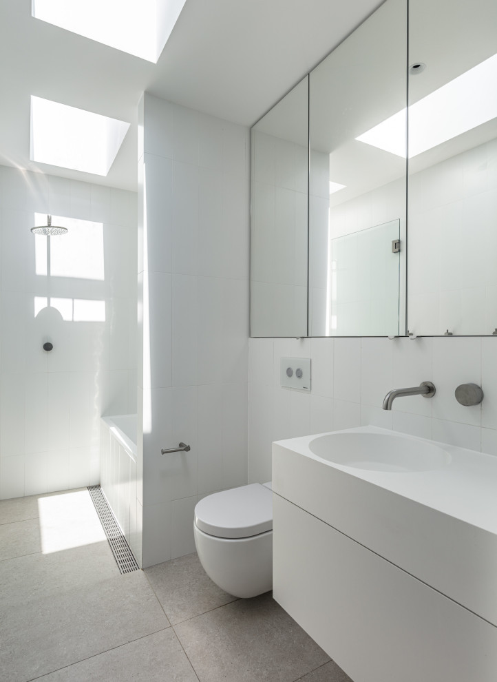 Идея дизайна: ванная комната в стиле модернизм с плоскими фасадами, белыми фасадами, ванной в нише, душевой комнатой, инсталляцией, белой плиткой, монолитной раковиной, серым полом, открытым душем, белой столешницей, тумбой под одну раковину и подвесной тумбой
