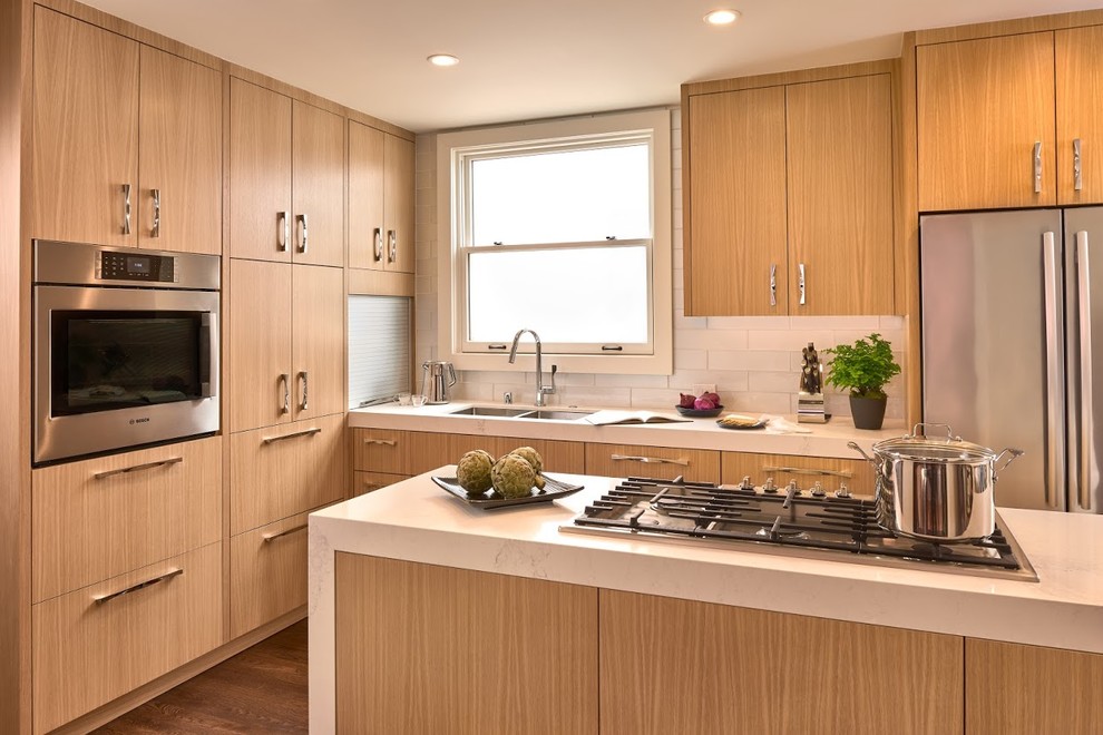 Inspiration for a mid-sized contemporary l-shaped eat-in kitchen in San Francisco with a double-bowl sink, flat-panel cabinets, light wood cabinets, quartzite benchtops, white splashback, subway tile splashback, white appliances, dark hardwood floors, with island and brown floor.