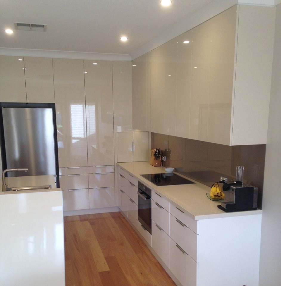 This is an example of a mid-sized contemporary kitchen in Adelaide with solid surface benchtops, metallic splashback, glass sheet splashback, stainless steel appliances and with island.