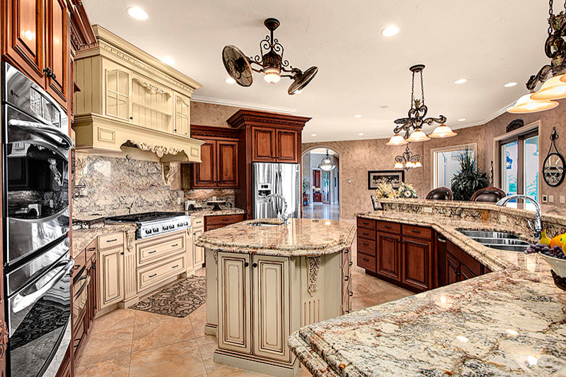Example of a tuscan ceramic tile kitchen design in Seattle with a triple-bowl sink, raised-panel cabinets, medium tone wood cabinets, granite countertops, stone slab backsplash, stainless steel appliances and two islands