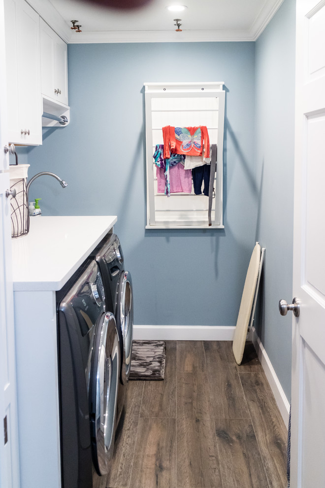 Example of a mid-sized transitional single-wall porcelain tile and brown floor dedicated laundry room design in New York with an undermount sink, shaker cabinets, white cabinets, quartz countertops, blue walls and a side-by-side washer/dryer