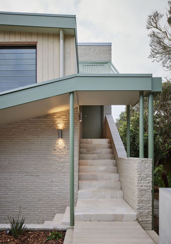 Mittelgroßes, Zweistöckiges Maritimes Einfamilienhaus mit Backsteinfassade, beiger Fassadenfarbe, Satteldach, Blechdach und Wandpaneelen in Melbourne