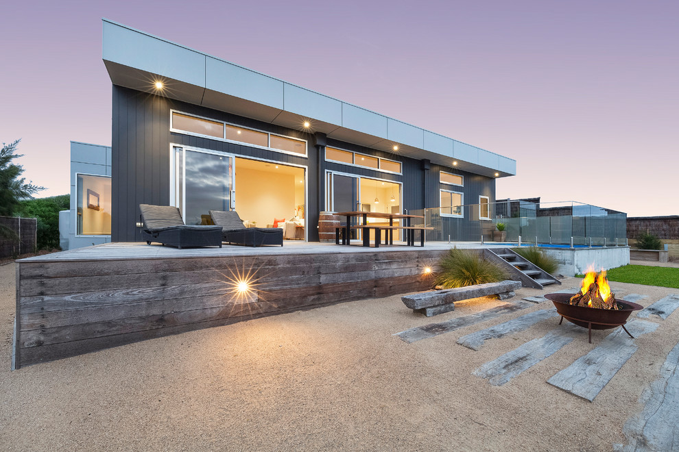 This is an example of a beach style one-storey black house exterior in Melbourne with a flat roof.