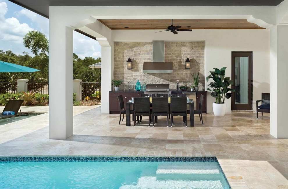 Inspiration for a mid-sized traditional backyard patio in Orlando with an outdoor kitchen, natural stone pavers and a roof extension.
