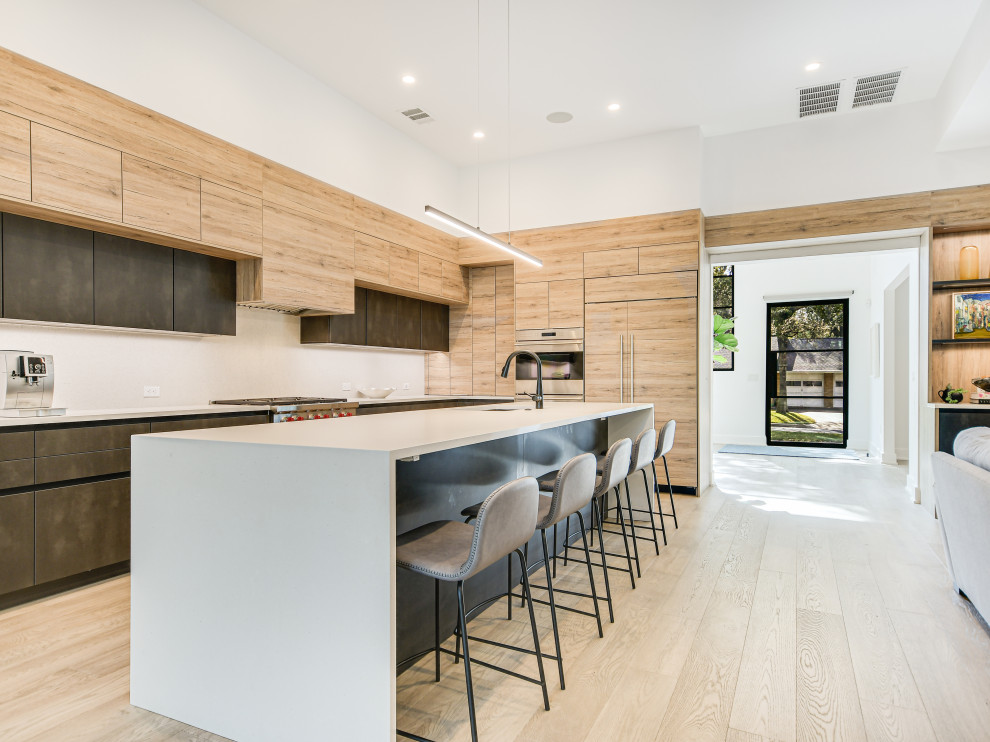Large contemporary l-shaped kitchen in Austin with an undermount sink, flat-panel cabinets, grey cabinets, stainless steel appliances, light hardwood floors, with island, beige floor and white benchtop.