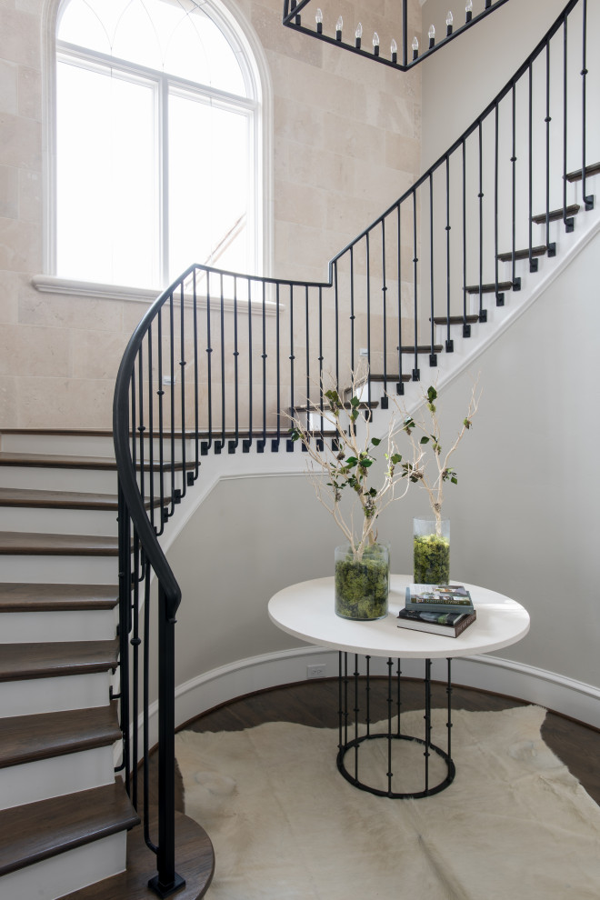 Large transitional wood curved staircase in Dallas with painted wood risers and metal railing.
