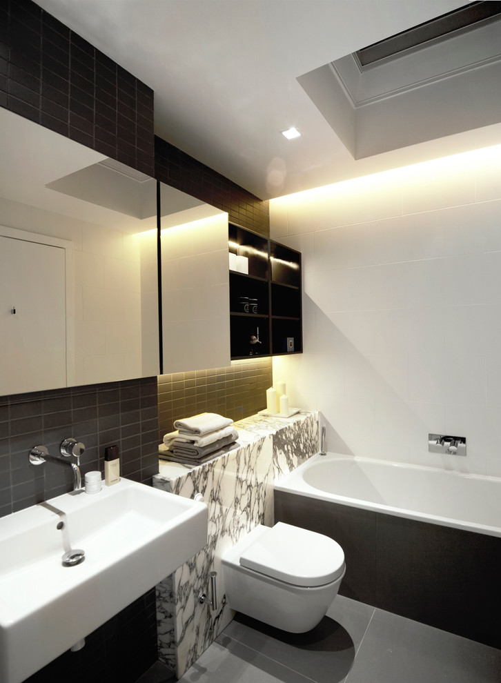 Inspiration for a large contemporary master bathroom in London with a wall-mount sink, marble benchtops, a drop-in tub, a wall-mount toilet, porcelain tile and porcelain floors.
