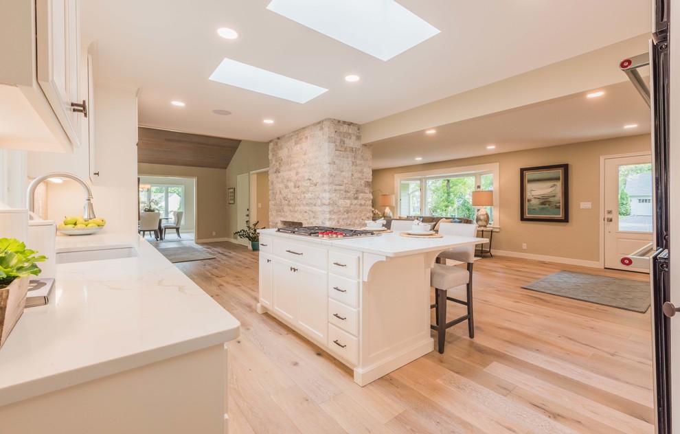 Eat-in kitchen - mid-sized l-shaped light wood floor and brown floor eat-in kitchen idea in Minneapolis with an undermount sink, shaker cabinets, white cabinets, beige backsplash, stainless steel appliances, an island, white countertops, quartz countertops and matchstick tile backsplash