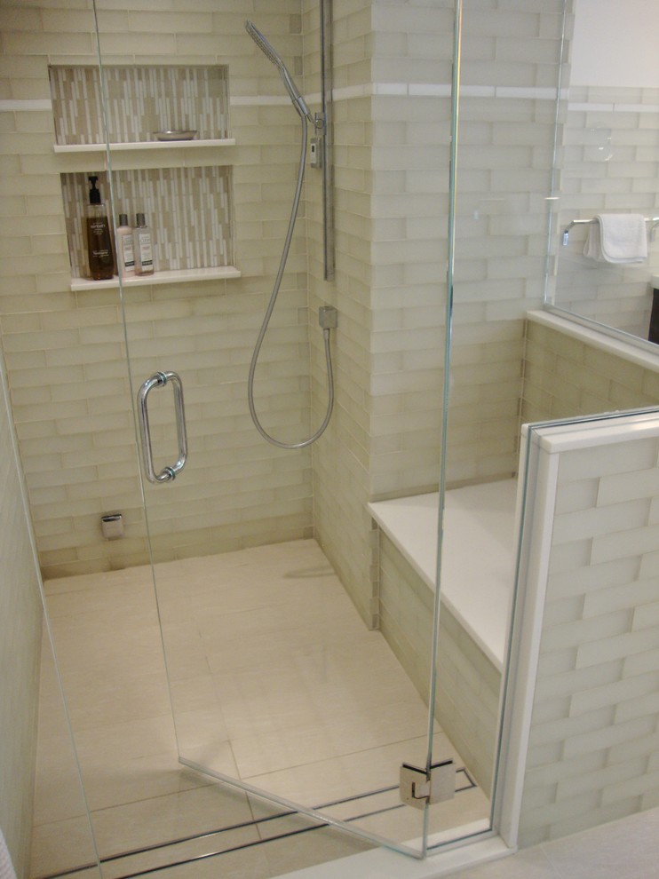 This is an example of a transitional bathroom in New York with an undermount sink, a freestanding tub, a corner shower, a one-piece toilet, beige tile and glass tile.