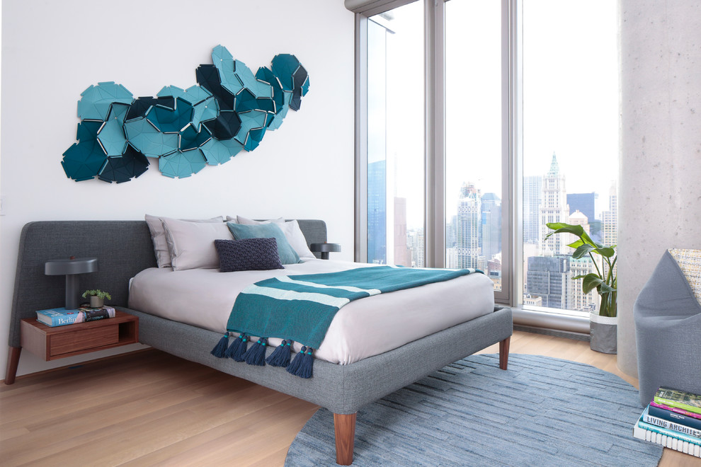 Inspiration for a contemporary bedroom in New York with white walls, light hardwood floors and brown floor.