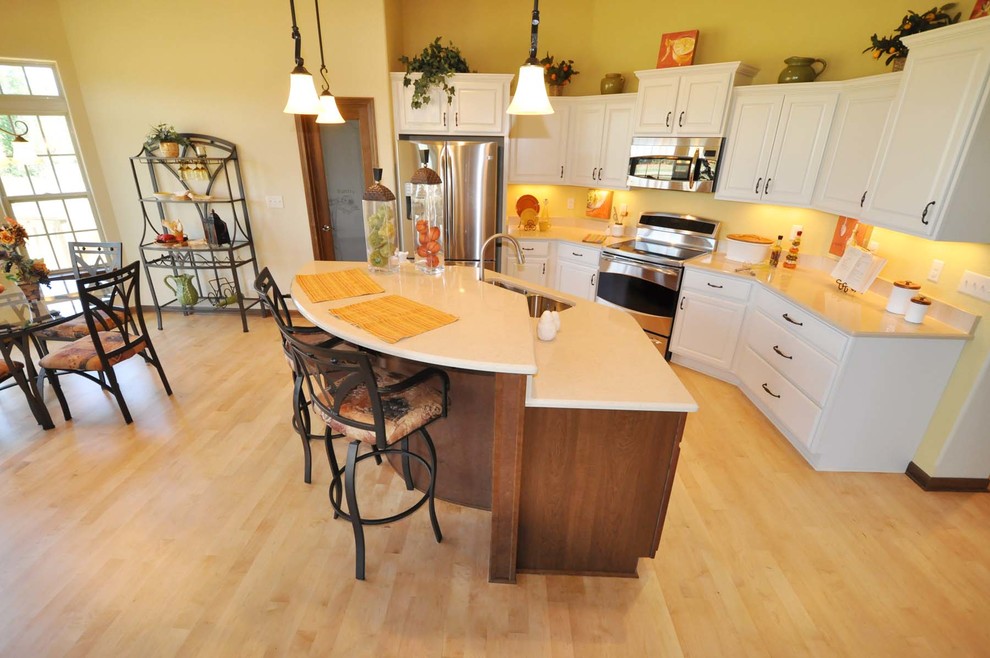 Mid-sized traditional l-shaped eat-in kitchen in Milwaukee with an undermount sink, shaker cabinets, medium wood cabinets, granite benchtops, stainless steel appliances, light hardwood floors and with island.