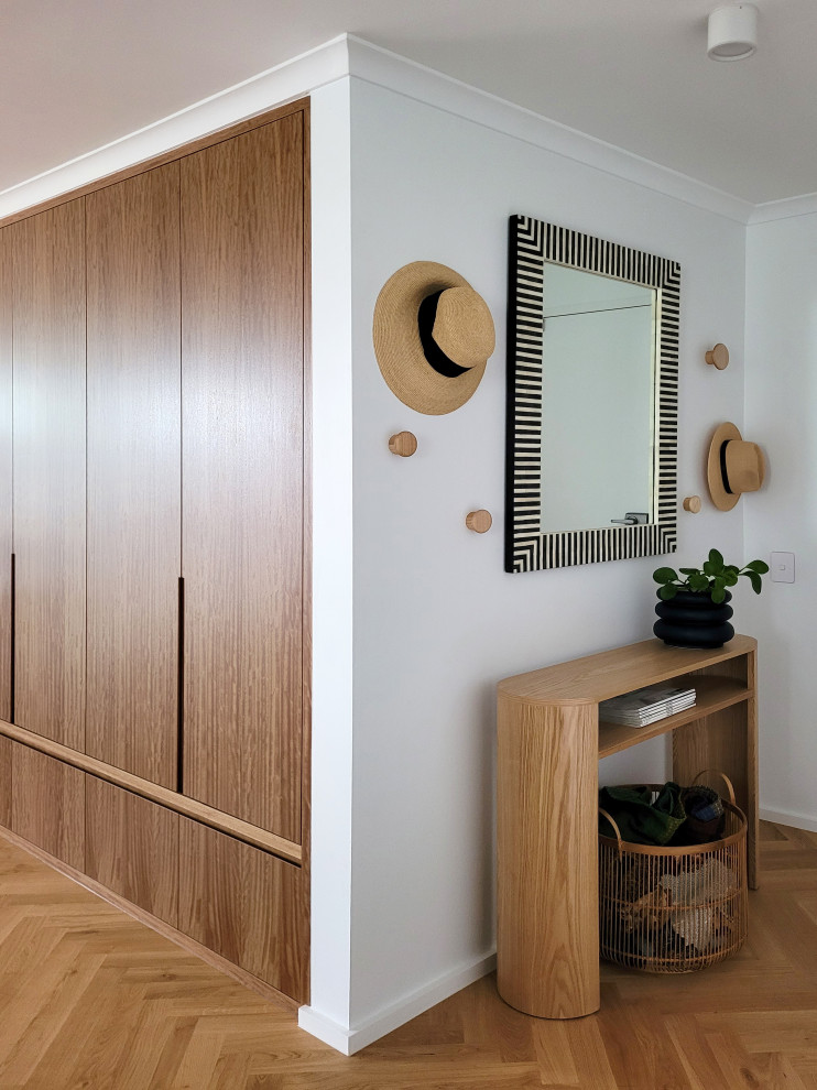 Small scandinavian foyer in Brisbane with white walls, light hardwood floors and brown floor.