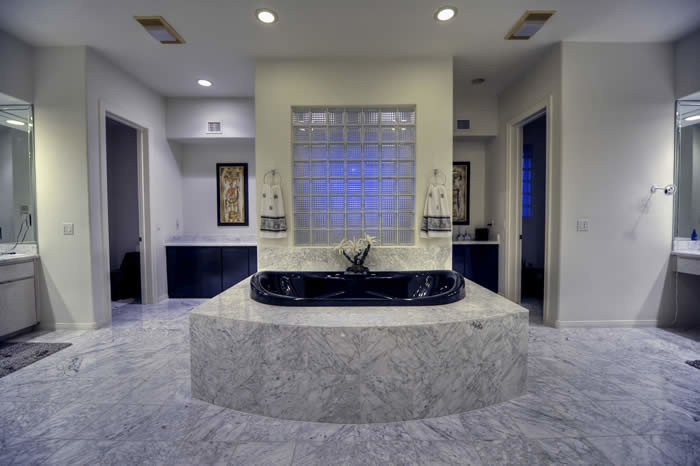 Photo of an expansive traditional 3/4 bathroom in Phoenix with furniture-like cabinets, light wood cabinets, a drop-in tub, an open shower, a two-piece toilet, beige tile, mosaic tile, beige walls, marble floors, a vessel sink and engineered quartz benchtops.