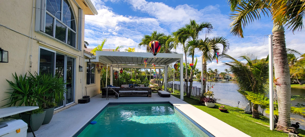 Photo of a mid-sized contemporary backyard patio in Miami with concrete slab and a pergola.