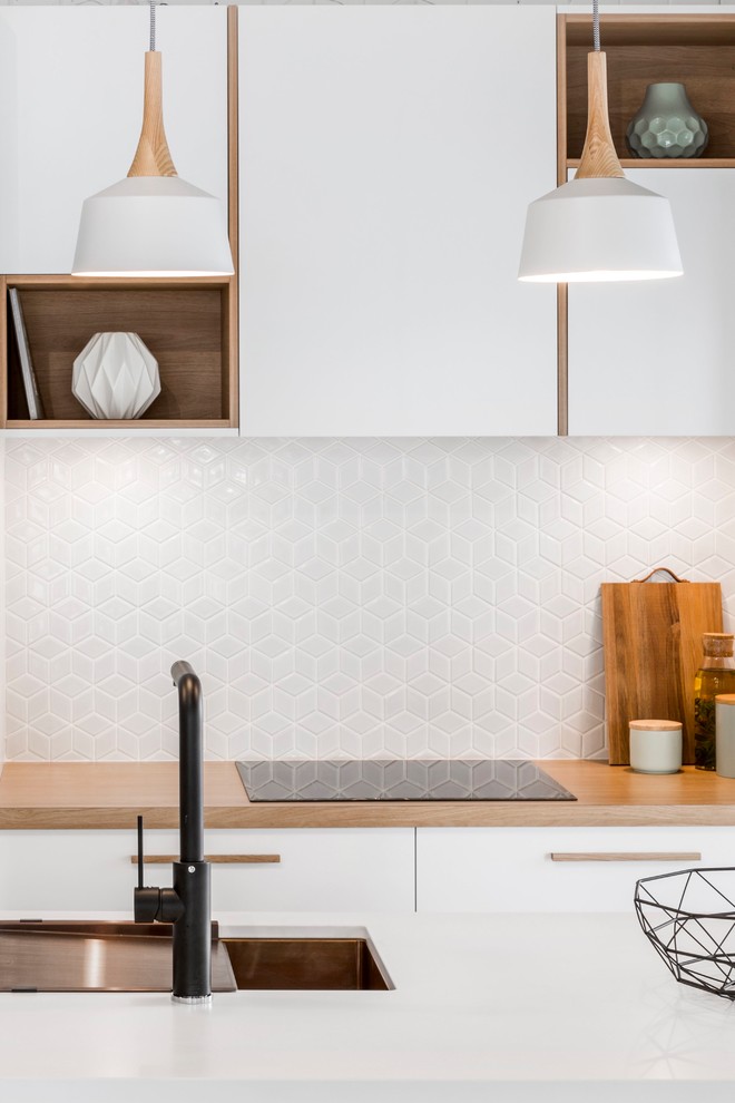 Kitchen - scandinavian galley ceramic tile kitchen idea in Brisbane with an undermount sink, flat-panel cabinets, white cabinets, quartz countertops, white backsplash, ceramic backsplash, stainless steel appliances and an island