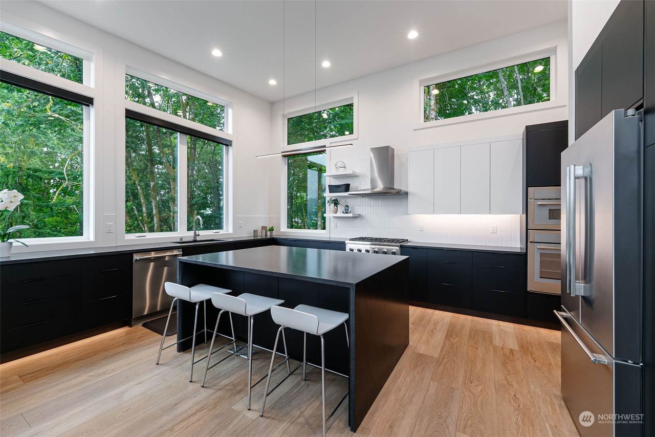 A spacious, modern kitchen with large windows that provide ample natural light. The kitchen features high-end appliances, sleek cabinetry, and a large island perfect for cooking and entertaining.