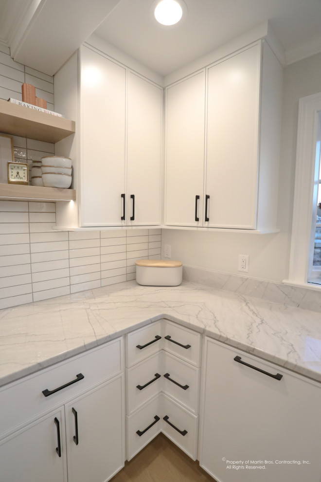Large transitional u-shaped light wood floor open concept kitchen photo with an undermount sink, flat-panel cabinets, white cabinets, quartzite countertops, white backsplash, porcelain backsplash, stainless steel appliances, an island and white countertops