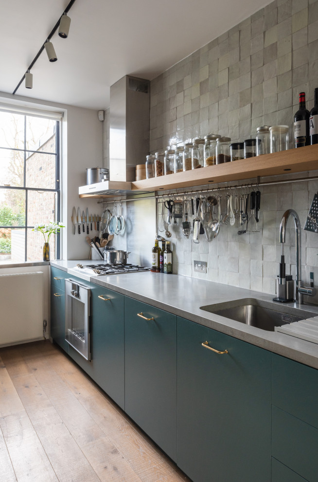 Inspiration for a contemporary kitchen in London with an undermount sink, flat-panel cabinets, blue cabinets, grey splashback, stainless steel appliances, medium hardwood floors, no island, brown floor and grey benchtop.