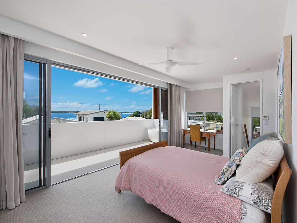 This is an example of a beach style bedroom in Sunshine Coast with white walls, carpet and beige floor.