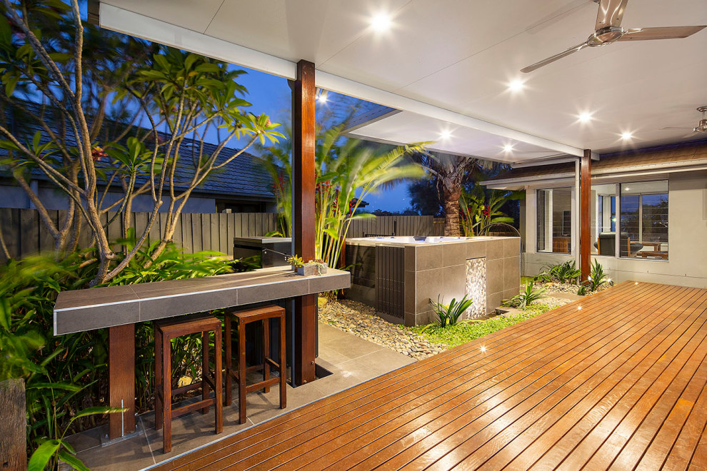 Ispirazione per un giardino tropicale esposto a mezz'ombra dietro casa con un focolare, pedane e recinzione in legno