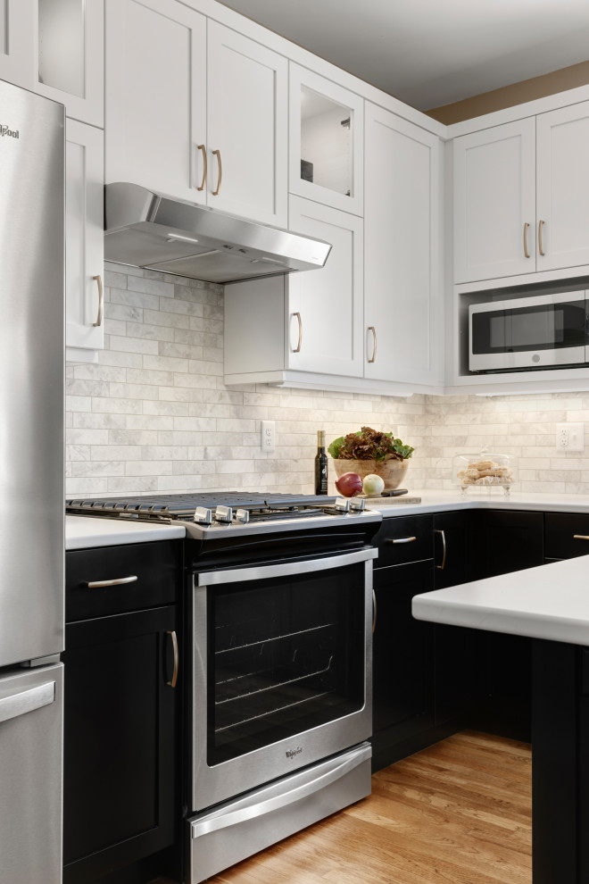 Example of a mid-sized transitional l-shaped medium tone wood floor and brown floor eat-in kitchen design in Minneapolis with an undermount sink, recessed-panel cabinets, black cabinets, quartz countertops, beige backsplash, stone tile backsplash, stainless steel appliances, an island and white countertops