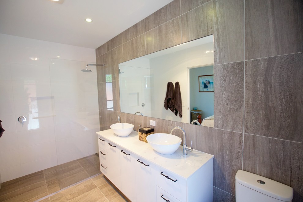Mid-sized traditional master bathroom in Sunshine Coast with a vessel sink, white cabinets, an open shower, gray tile, grey walls, flat-panel cabinets, engineered quartz benchtops, a one-piece toilet, ceramic tile and ceramic floors.