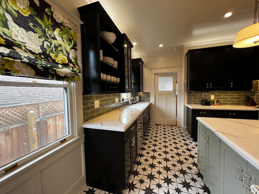 This is an example of a large classic u-shaped kitchen in San Francisco with a belfast sink, flat-panel cabinets, black cabinets, engineered stone countertops, green splashback, ceramic splashback, stainless steel appliances, porcelain flooring, an island, black floors and white worktops.