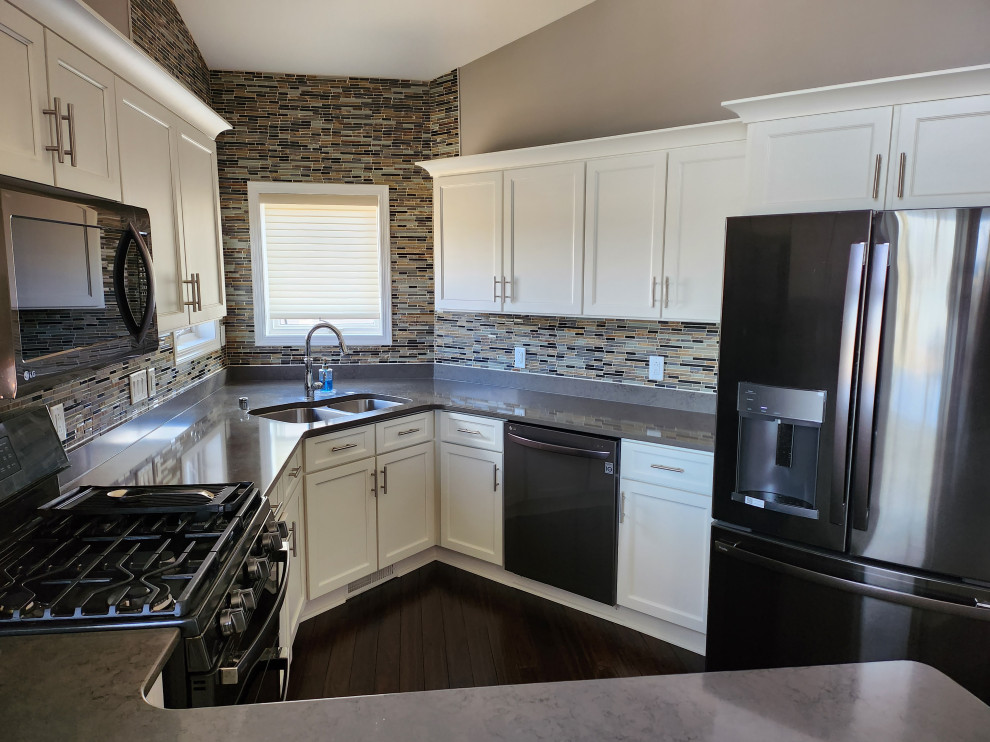 Example of a mid-sized transitional u-shaped dark wood floor and brown floor open concept kitchen design with an undermount sink, shaker cabinets, yellow cabinets, quartzite countertops, brown backsplash, glass tile backsplash, stainless steel appliances, a peninsula and gray countertops