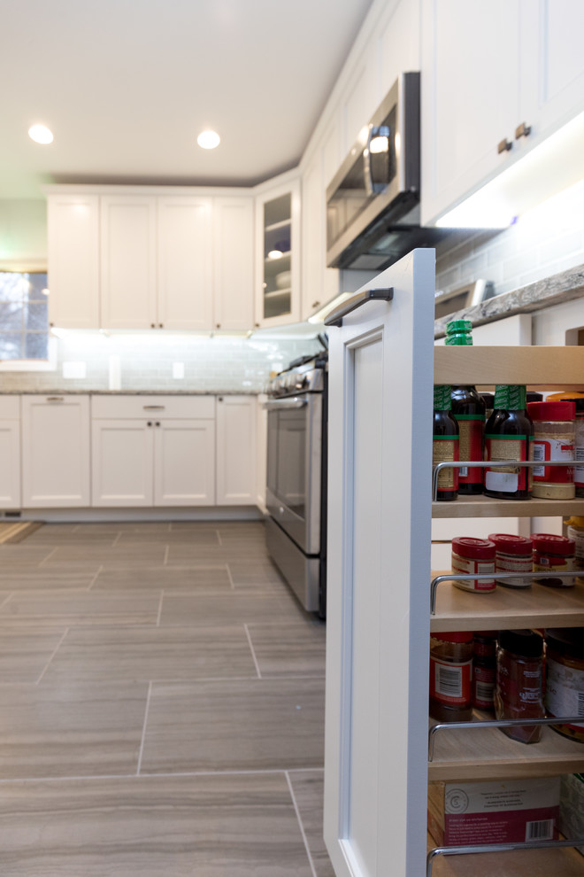 Inspiration for a mid-sized transitional l-shaped porcelain tile and brown floor enclosed kitchen remodel in San Diego with an undermount sink, beaded inset cabinets, white cabinets, granite countertops, gray backsplash, ceramic backsplash, stainless steel appliances, no island and gray countertops