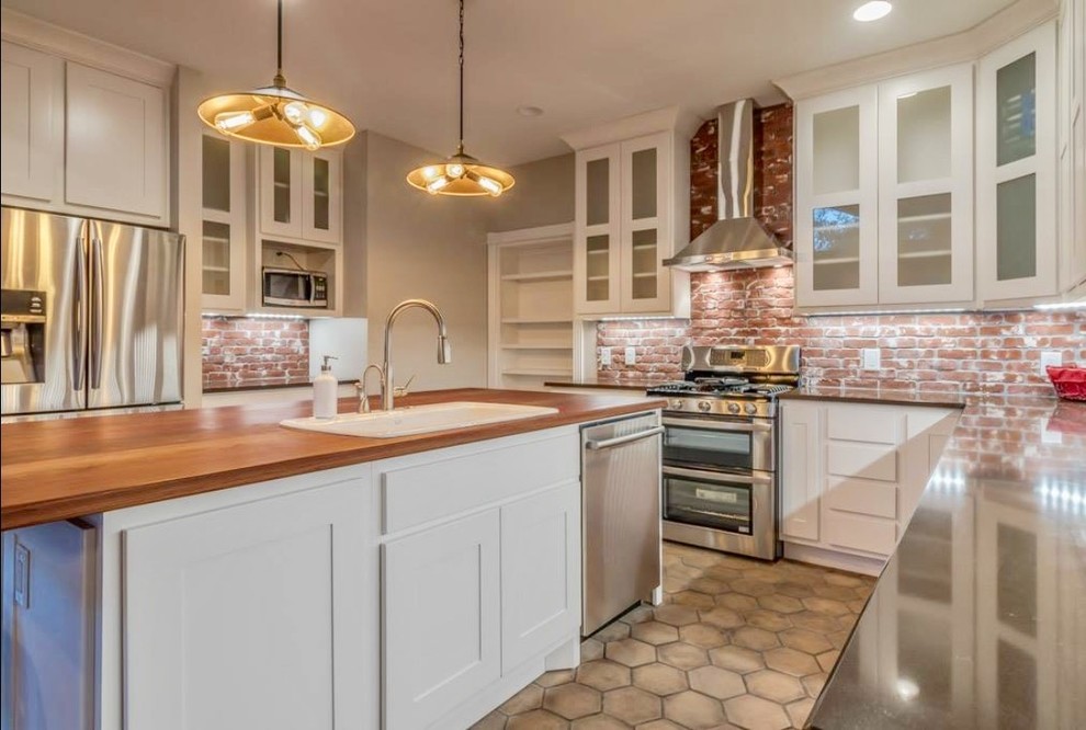 Example of a large transitional u-shaped beige floor and terra-cotta tile enclosed kitchen design in Austin with a drop-in sink, shaker cabinets, white cabinets, red backsplash, brick backsplash, stainless steel appliances, an island, gray countertops and granite countertops