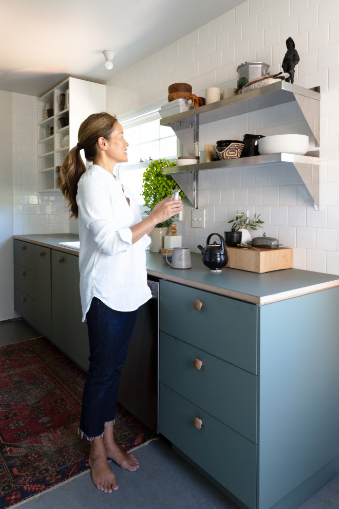 This is an example of a mid-sized scandinavian galley separate kitchen in Portland with a drop-in sink, flat-panel cabinets, green cabinets, laminate benchtops, white splashback, ceramic splashback, stainless steel appliances, linoleum floors, no island, green floor and green benchtop.