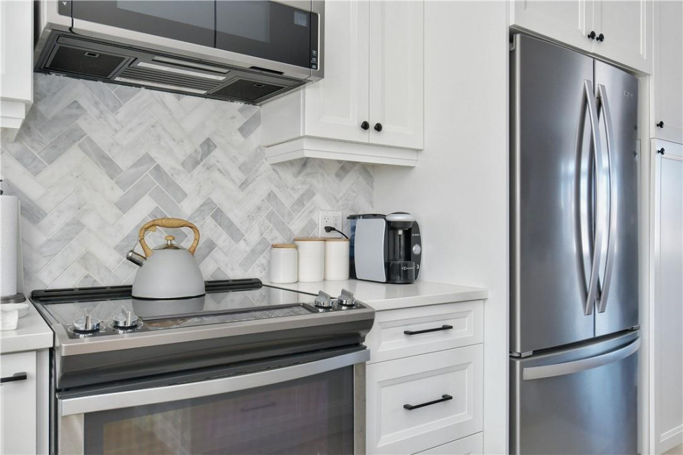 Idéer för att renovera ett mellanstort funkis vit vitt kök, med luckor med upphöjd panel, vita skåp, bänkskiva i kvartsit, grått stänkskydd, stänkskydd i keramik, laminatgolv, en köksö och beiget golv