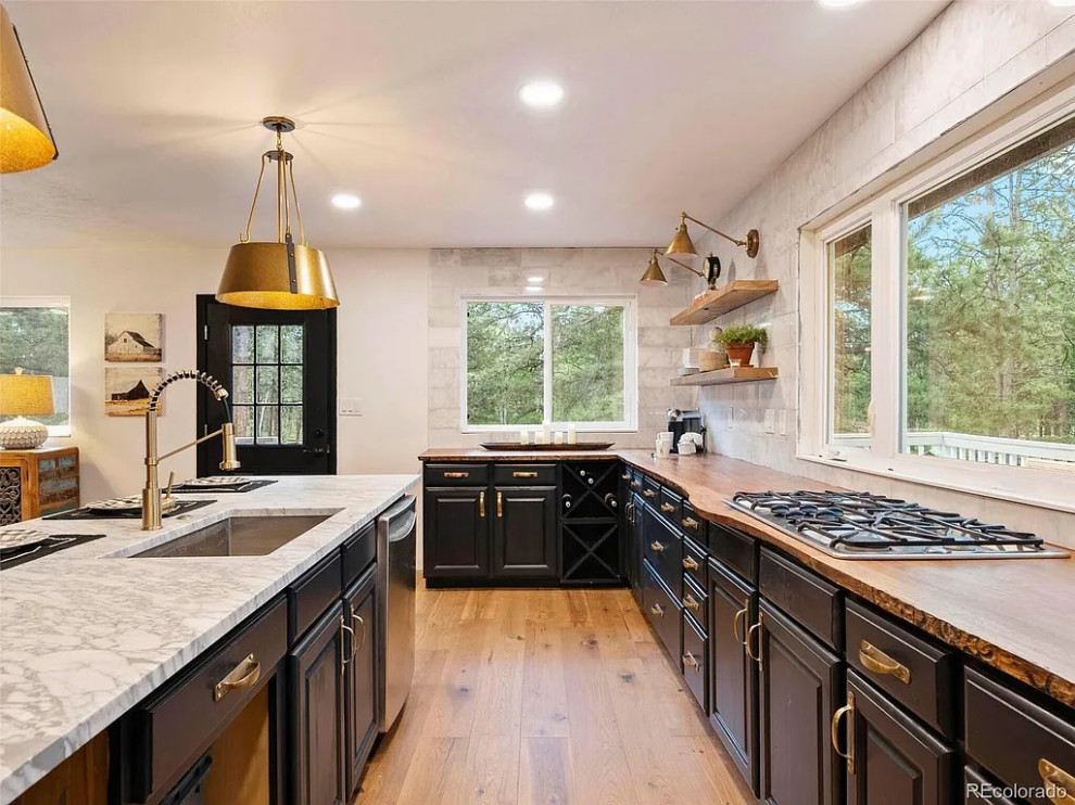 Large transitional u-shaped medium tone wood floor and brown floor open concept kitchen photo in Denver with an undermount sink, raised-panel cabinets, black cabinets, wood countertops, white backsplash, marble backsplash, stainless steel appliances, an island and brown countertops