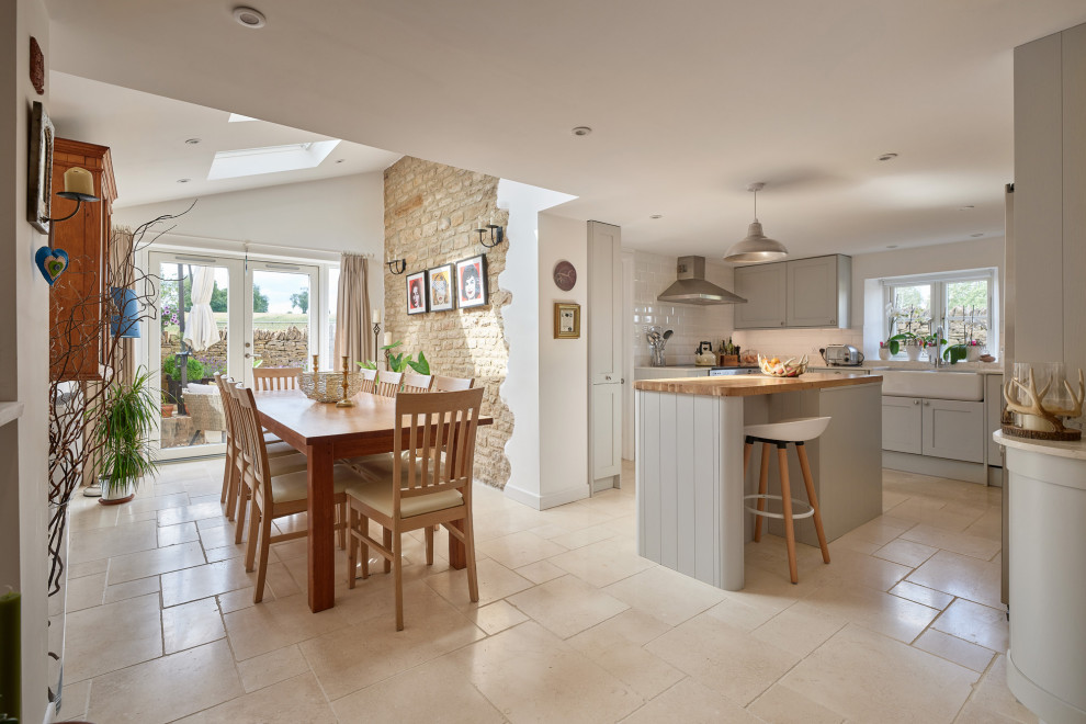 Kleine Klassische Wohnküche mit weißer Wandfarbe, Porzellan-Bodenfliesen, Kaminofen, Kaminumrandung aus Stein, beigem Boden und Ziegelwänden in Oxfordshire