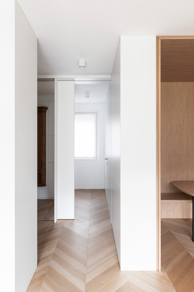 Inspiration pour un petit couloir design avec un mur blanc, parquet clair, un sol marron et boiseries.