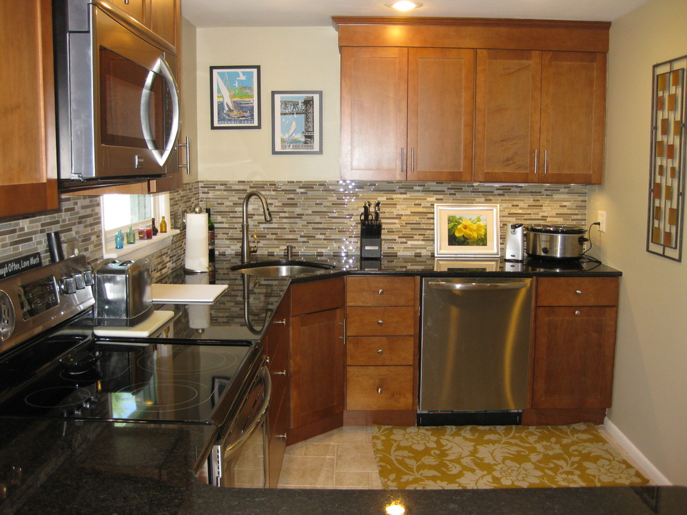 Example of a transitional u-shaped travertine floor and beige floor eat-in kitchen design in Boston with an undermount sink, medium tone wood cabinets, granite countertops, stainless steel appliances, a peninsula, shaker cabinets, brown backsplash, matchstick tile backsplash and black countertops