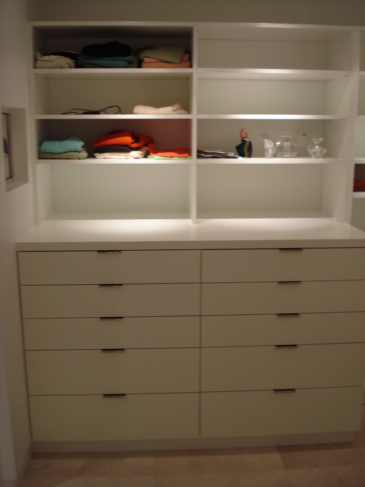 This is an example of a mid-sized beach style gender-neutral walk-in wardrobe in Miami with white cabinets.