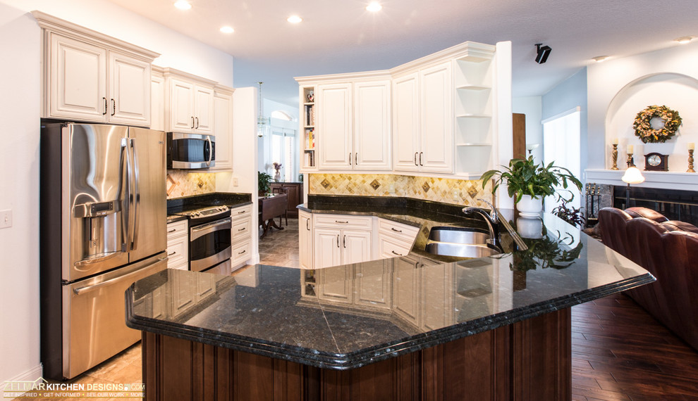 Photo of a traditional u-shaped eat-in kitchen in Orlando with an undermount sink, raised-panel cabinets, white cabinets, granite benchtops, white splashback, stone tile splashback, stainless steel appliances, travertine floors and a peninsula.
