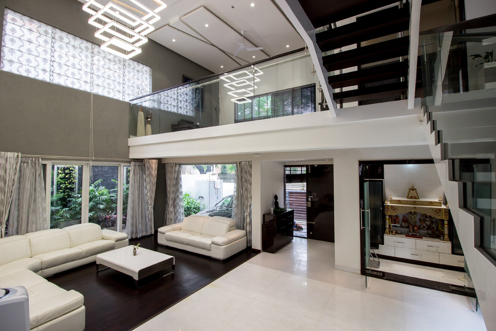 This is an example of a large contemporary living room in Bengaluru with white walls and dark hardwood floors.
