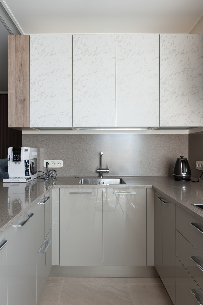 Photo of a mid-sized contemporary u-shaped eat-in kitchen in Saint Petersburg with an undermount sink, flat-panel cabinets, beige cabinets, solid surface benchtops, beige splashback, porcelain floors, a peninsula, beige floor and beige benchtop.
