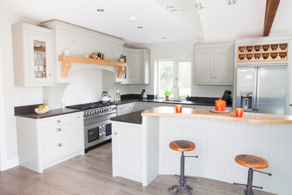 Photo of a mid-sized country l-shaped open plan kitchen in Dublin with an undermount sink, flat-panel cabinets, grey cabinets, quartzite benchtops, black splashback, cement tiles, with island and brown floor.