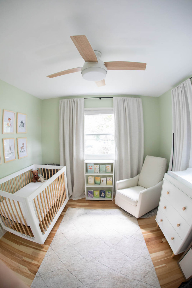 Ispirazione per una piccola cameretta per neonati neutra minimal con pareti verdi e parquet chiaro